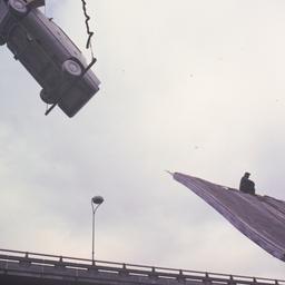Crane lifting white car.