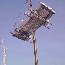 Crane lowering gray car.