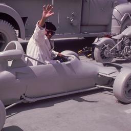 Man riding in gray racecar.