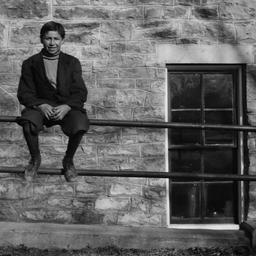 Young Man Sitting on a Fenc...