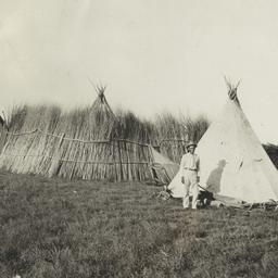 Man in a Yard with Two Tipi...