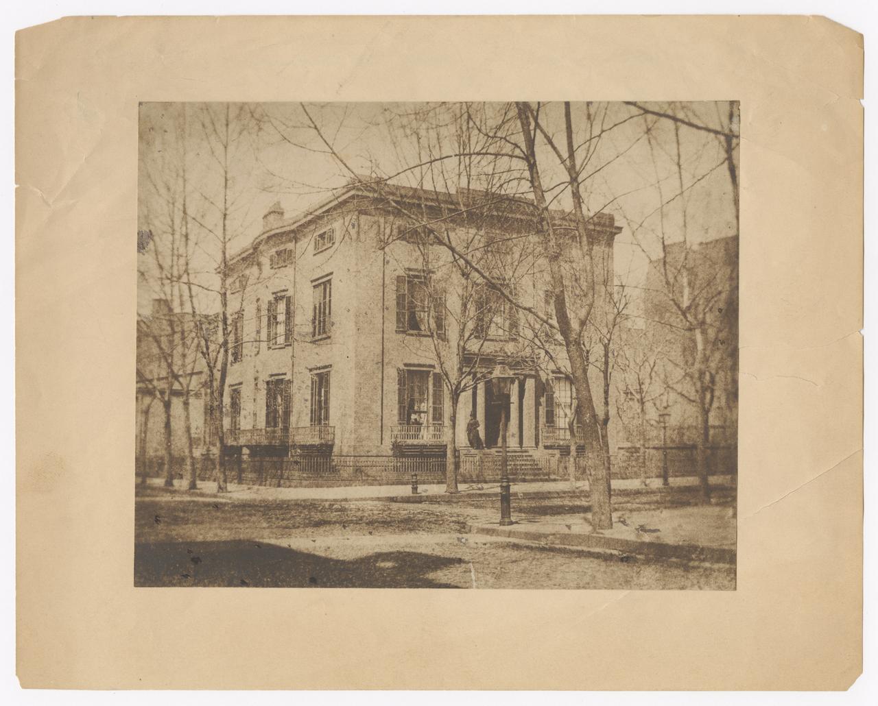 View of the De Rham house. Man stands at the entrance of the house.