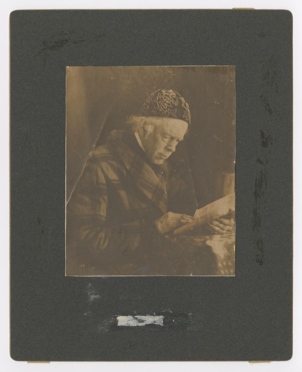 Nathaniel Fish Moore wearing an embroidered cap and reading a book.