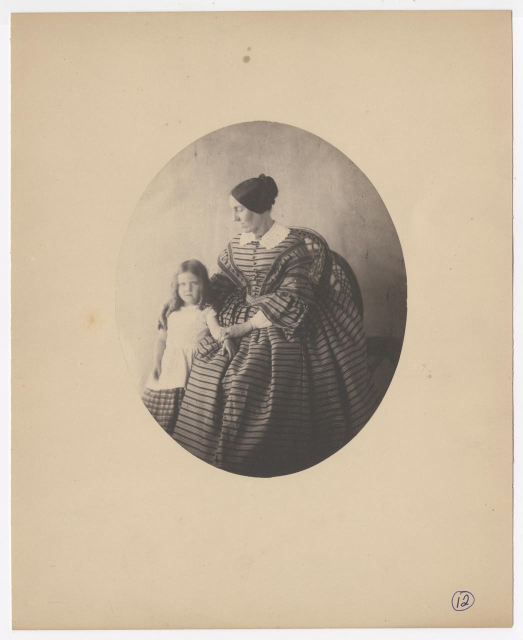 Woman in a large, striped dress is seated. A young girl stands by her side.