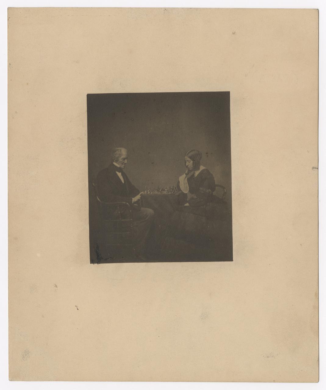 Moore and his daughter sit on opposite sides of a chess board.