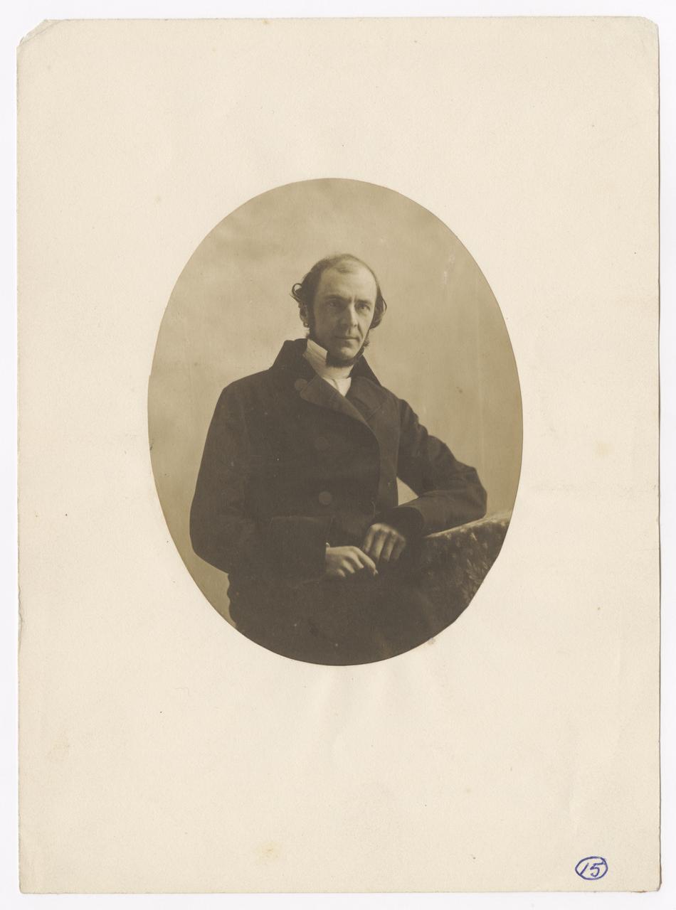 Man sits on chair, with his left elbow resting on a side table.